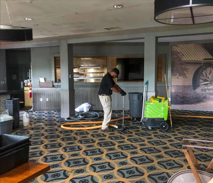 SERVPRO tech removing water from the carpet in a Woodstock, GA business