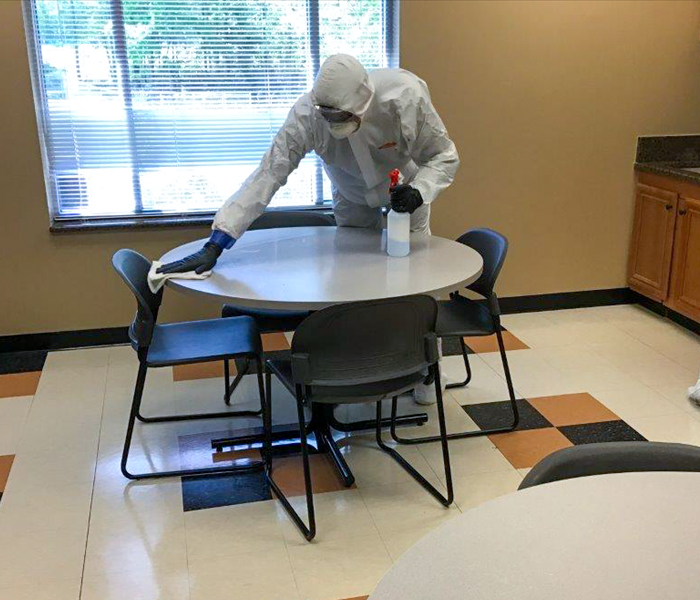 SERVPRO Technician in PPE cleaning a table
