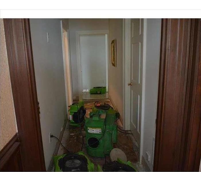 Air movers and drying equipment placed in the hallway of a home after water damage